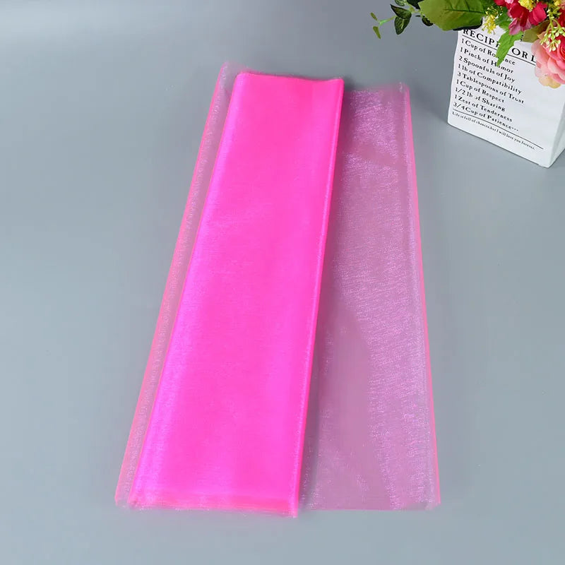 Folded pink tulle fabric on a gray surface with a box of flowers nearby.