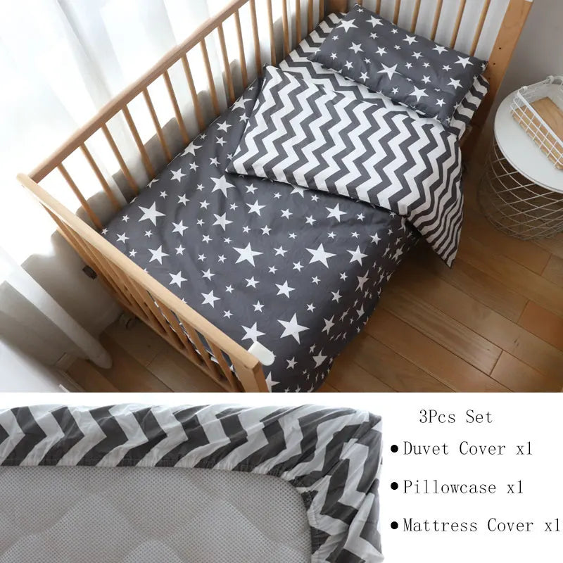 Wooden crib with a gray star-patterned bedding set, featuring a duvet cover, pillowcase, and mattress cover. A nearby table holds decor items, and soft sunlight streams in.