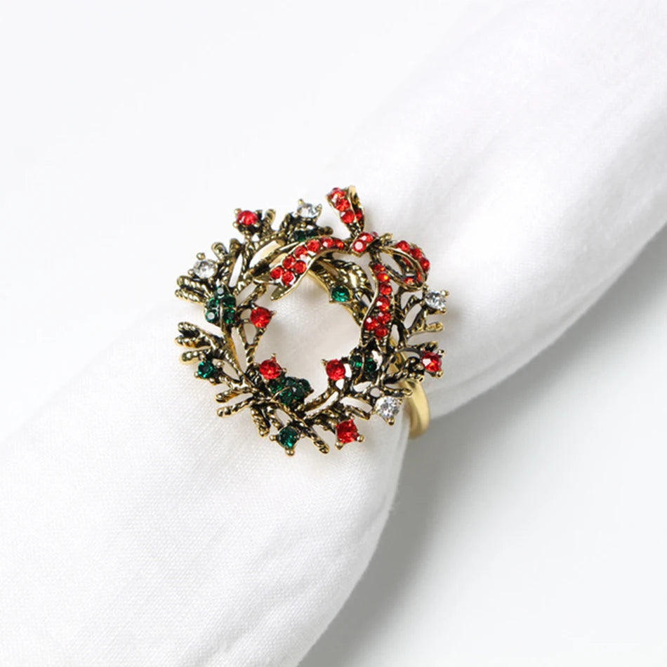Gold Christmas wreath napkin ring adorned with red, green, and white gemstones, securing a white napkin.
