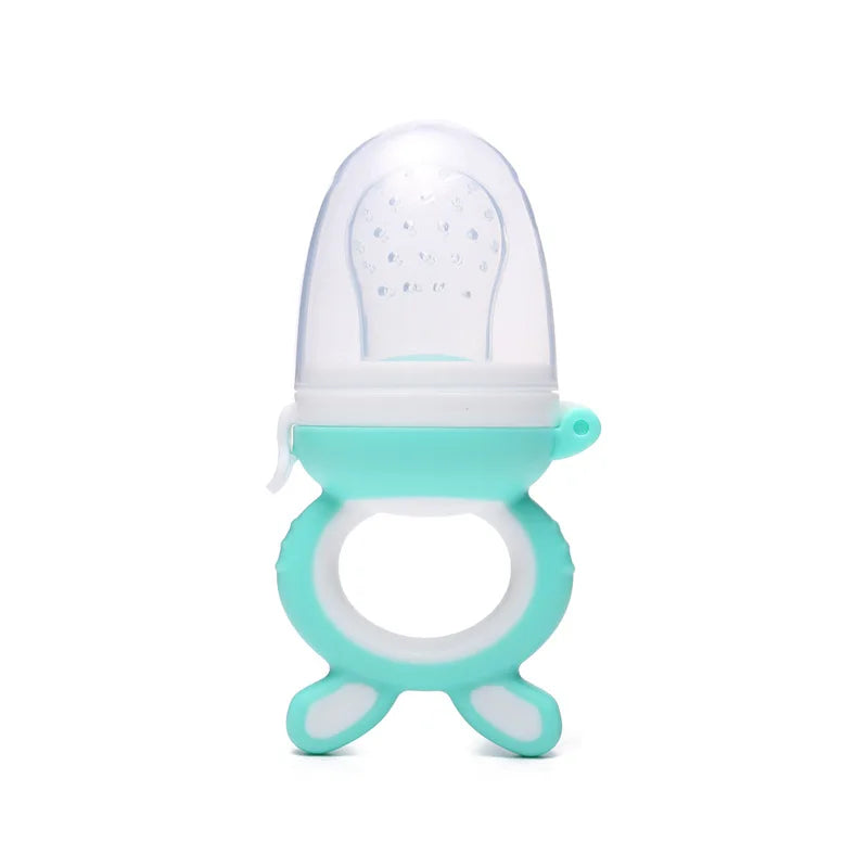 Turquoise baby fruit feeder with a transparent silicone top and a round handle with two stubby legs, designed for safely introducing solid foods to infants.