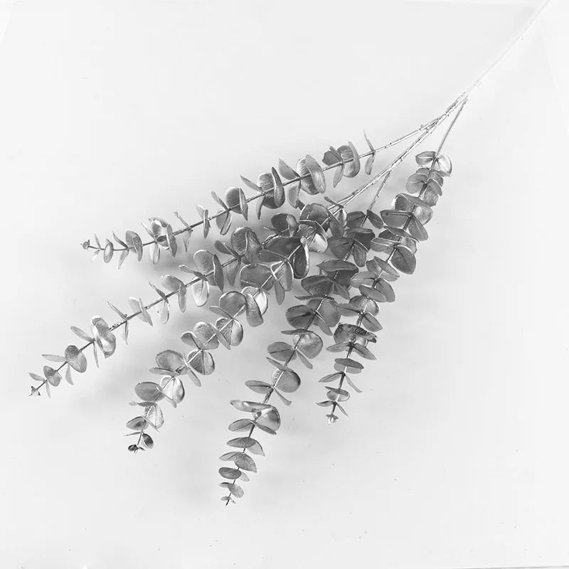 Black and white image of eucalyptus branches with round leaves arranged diagonally on a light background, showcasing their natural texture and unique leaf pattern.