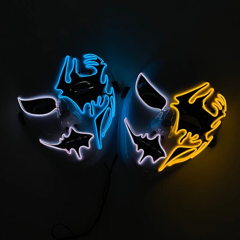 Two glowing masks with neon accents: one in blue and the other in yellow. Both masks feature abstract, dripping designs and symmetrical cutouts for eyes and mouths, set against a dark background.