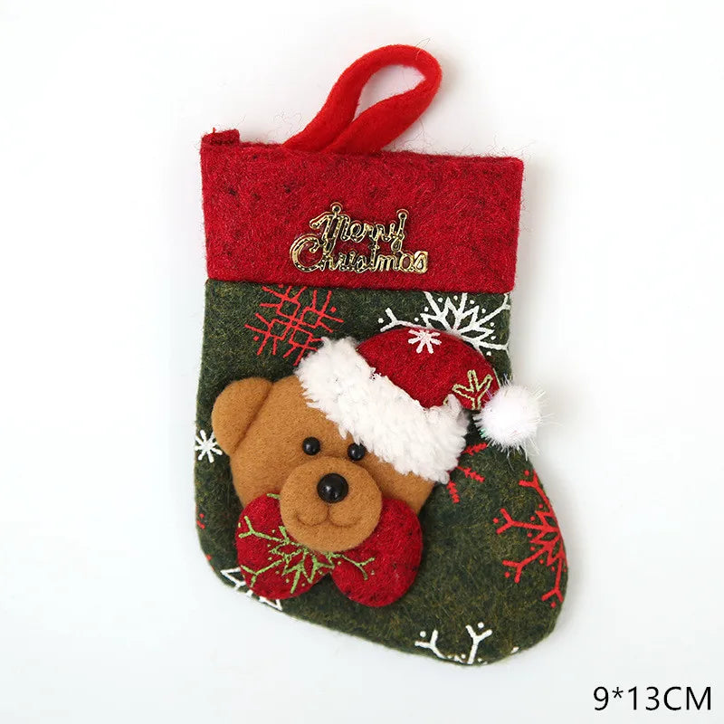 A small festive Christmas stocking featuring a teddy bear with a Santa hat, decorated with red and white snowflakes and "Merry Christmas" embroidery. Dimensions: 9x13 cm.