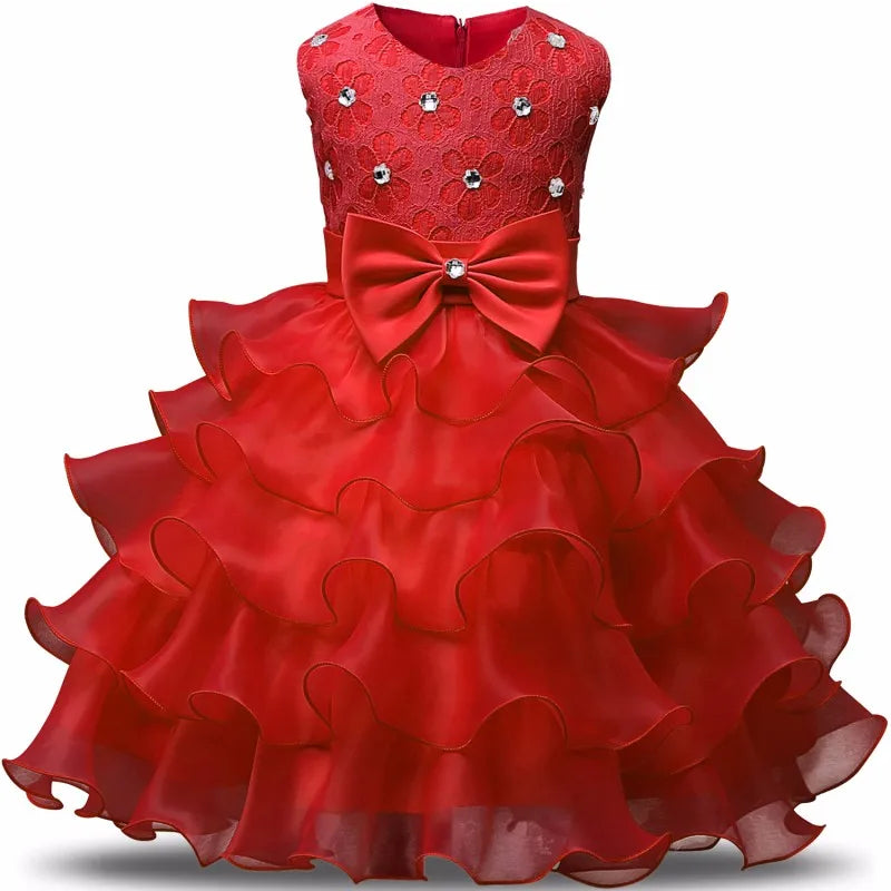 Red girls' dress with floral lace bodice, embellished with rhinestones. Features a large bow at the waist and multiple layered ruffled skirt, creating a voluminous look.