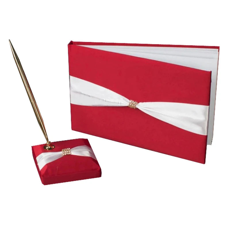 Red and white wedding guest book and pen set. The book and pen holder feature elegant white satin ribbons and a decorative rhinestone accent. The pen is gold-toned.