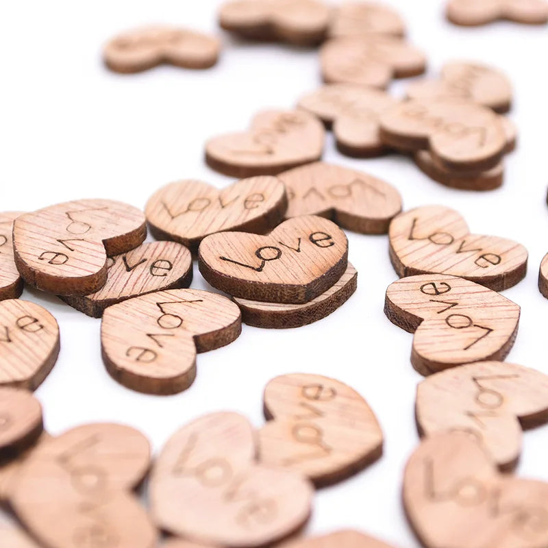Wooden heart-shaped tokens with the word "love" engraved, scattered on a white surface.