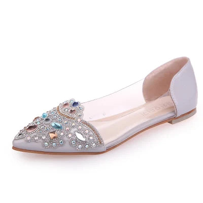 Elegant flat shoe with a pointed toe, featuring intricate gemstone and bead embellishments. The design includes various shapes and colors on a translucent-sided upper.