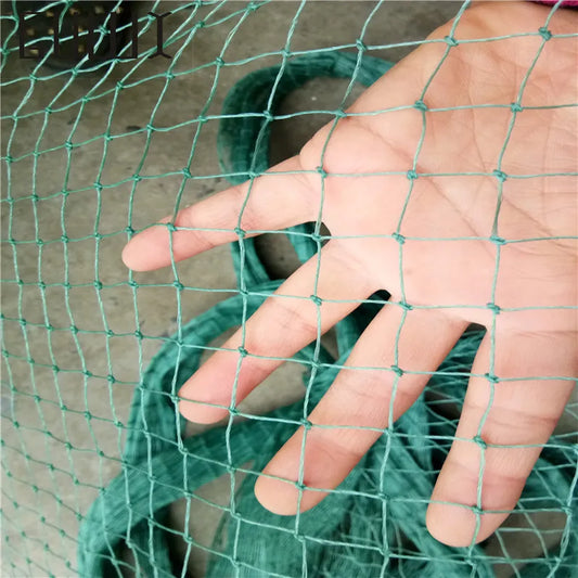 A person's hand is shown behind a green net with square holes, highlighting the texture and weave. The net appears to be lightweight and is partially draped in the background.