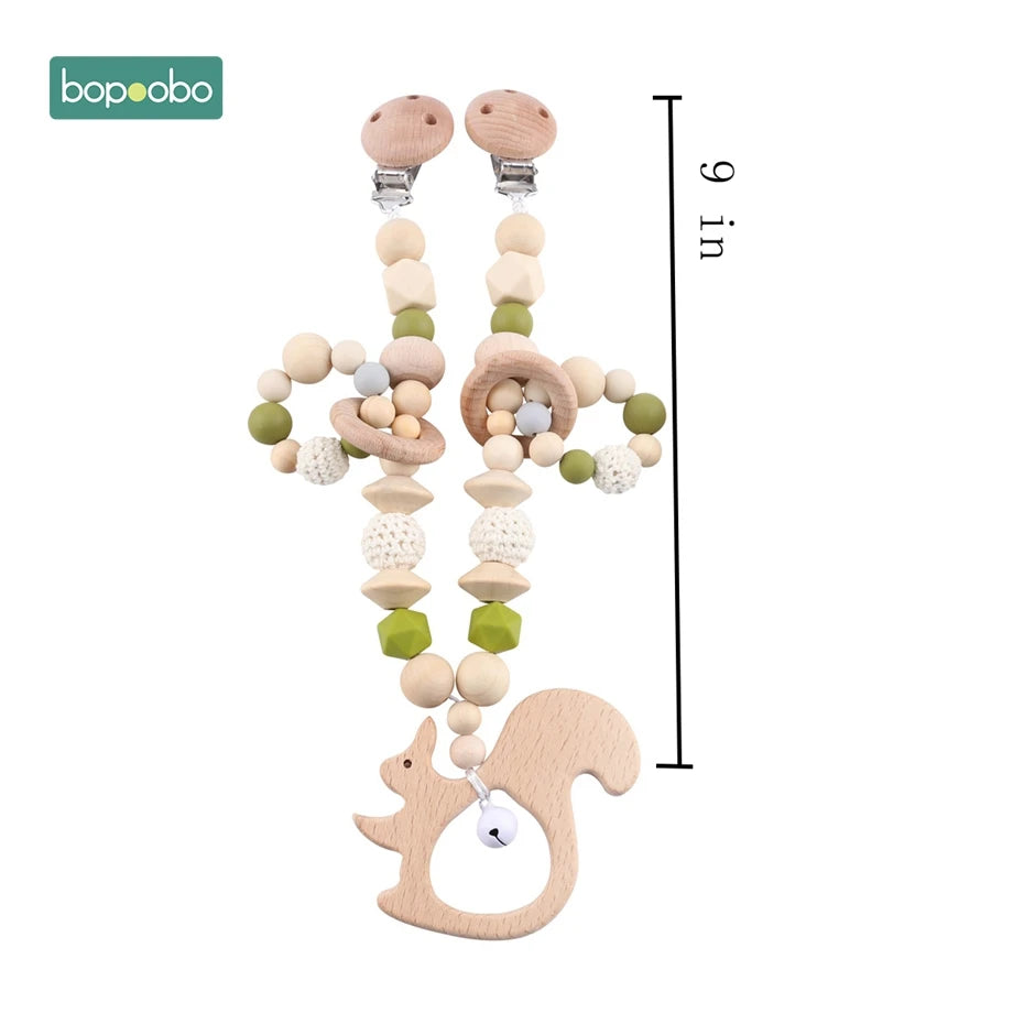 Wooden baby pacifier clip with beads and crochet details. Features a playful squirrel design and measures 9 inches long. Includes bopoobo branding at the top left.