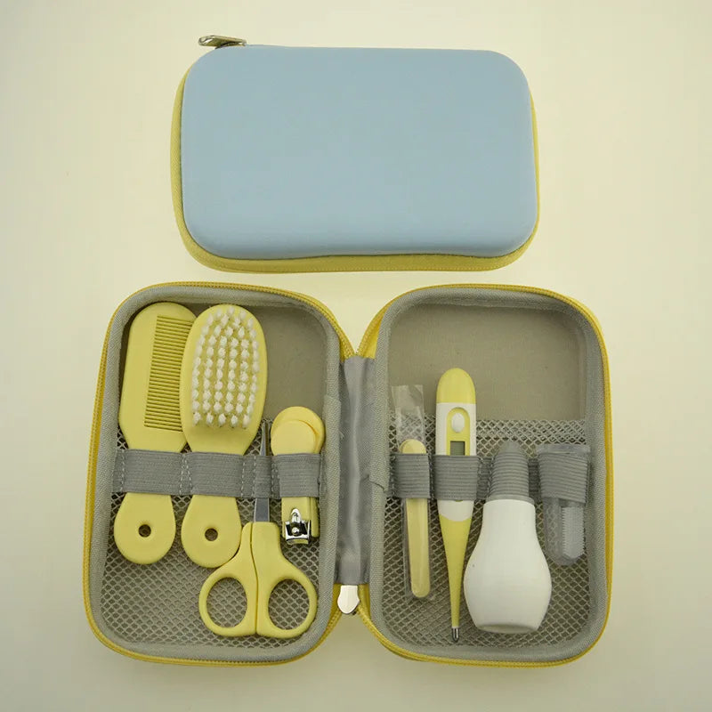 Open baby grooming kit with yellow tools including a comb, brush, nail clippers, scissors, thermometer, and nasal aspirator, set in a gray and yellow case.