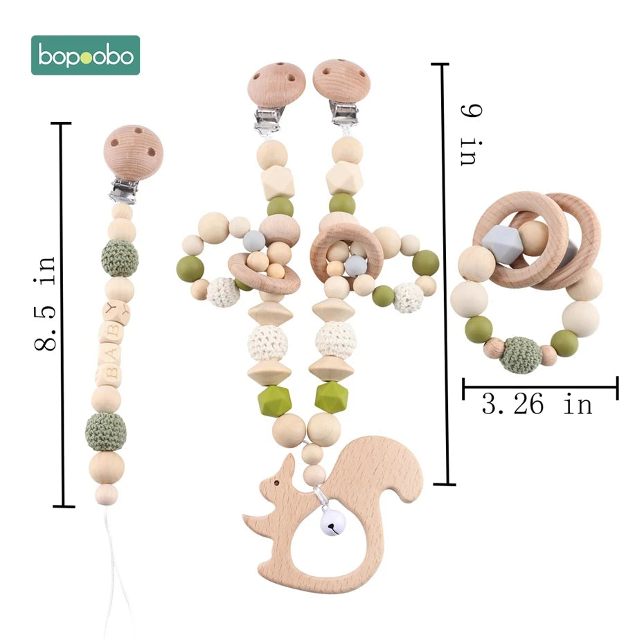 Wooden baby accessories set including two pacifier clips and a teething ring. Features crochet and wooden beads in natural and green colors. Measurements are provided.