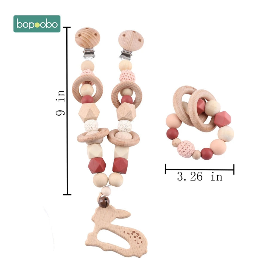 Wooden baby pacifier clip and teething ring set with pink, beige, and red beads. The clip is 9 inches long, and the ring is 3.26 inches in diameter, featuring a bunny shape.