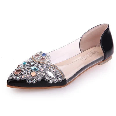 Black pointed flat shoe with transparent sides, featuring intricate rhinestone and bead embellishments on the toe. The insole is beige, and the outer sole is light brown.