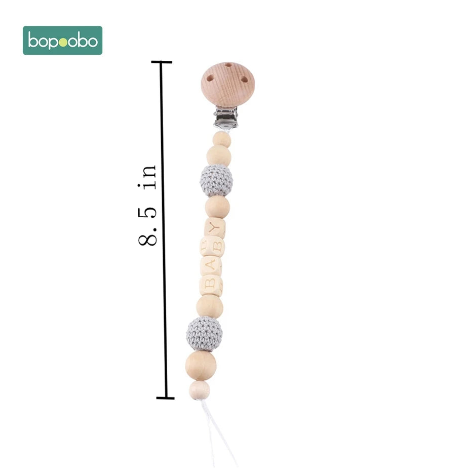 Wooden beaded pacifier clip with textured gray and letter beads spelling "BABY," measuring 8.5 inches long. Attached to a wooden clip with the brand "bopoobo" logo at the top.