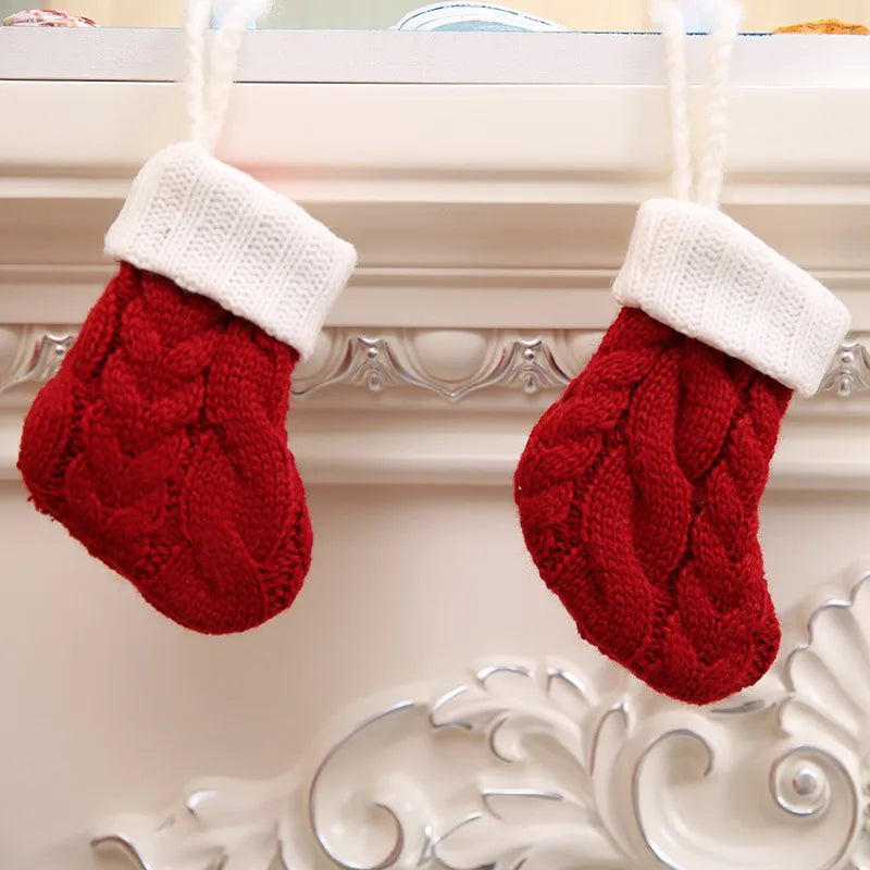 Two red knitted Christmas stockings with white cuffs hang from an ornate mantel.