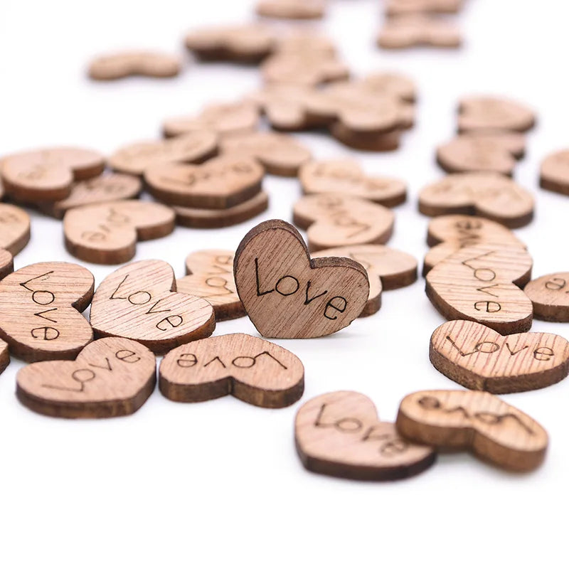 Scattered wooden heart-shaped pieces with the word "Love" engraved, focus on one standing prominently in the center, against a white background.