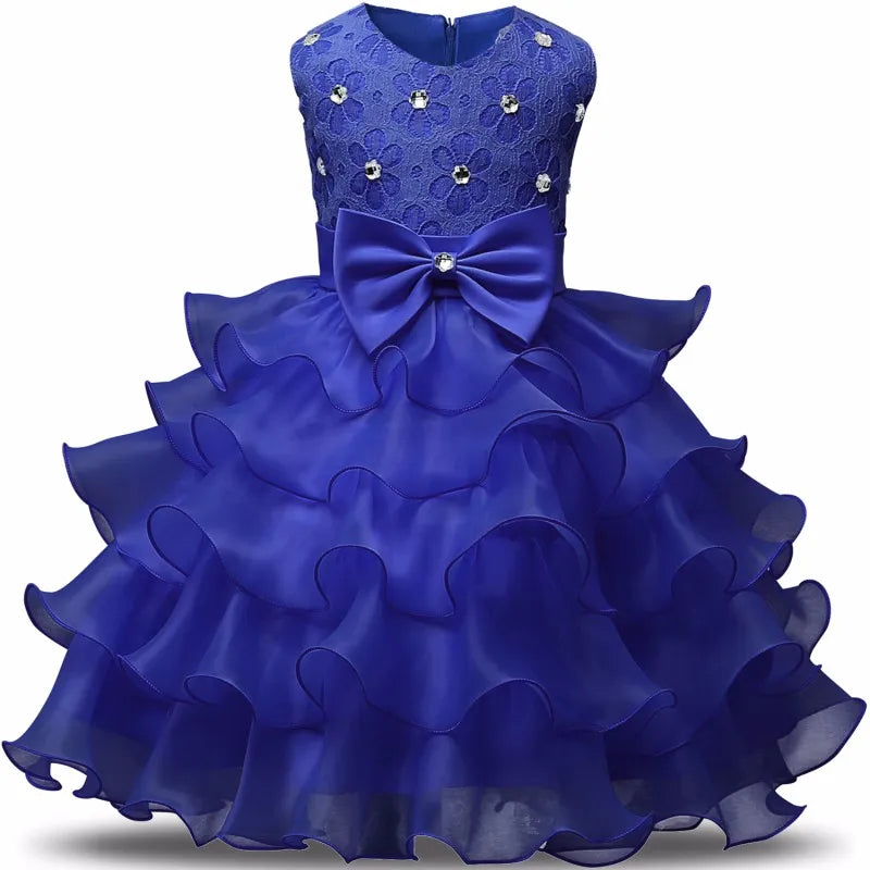 Bright blue ruffled dress for girls with a lace bodice, floral embellishments, and a large bow at the waist. Ideal for parties and special occasions.