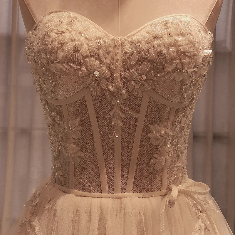 Elegant strapless gown with intricate floral lace and bead detailing on the bodice, featuring a fitted corset style and delicate tulle skirt overlay.