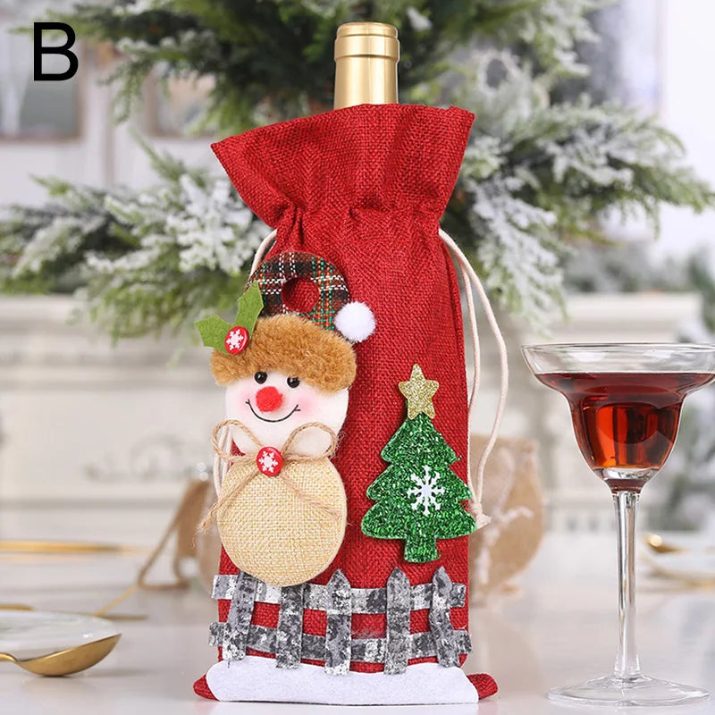Festive wine bottle in a red bag adorned with a snowman, Christmas tree, and plaid accents, sitting beside a filled wine glass. A frosted tree is blurred in the background.