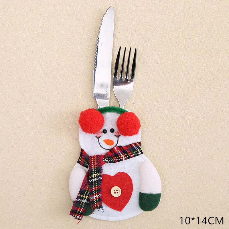 Festive cutlery holder shaped like a snowman, adorned with red earmuffs, plaid scarf, and heart decoration, holds a silver fork and knife on a beige background. Size marked as 10×14cm.