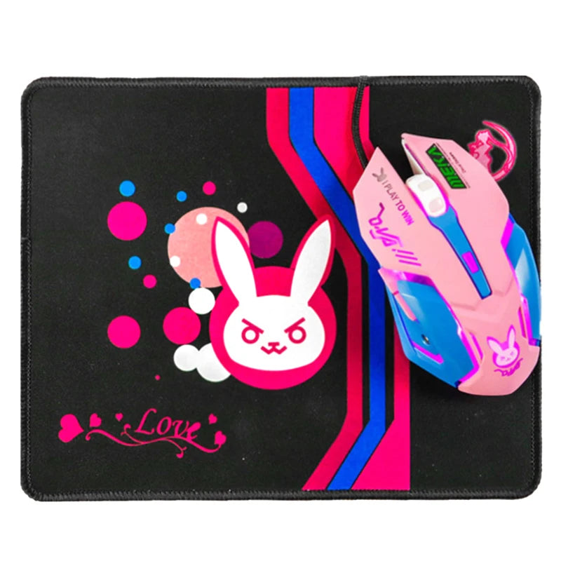 Pink gaming mouse on a black mousepad featuring a white bunny face, colorful circles, and stripes. The word "Love" is written in pink with heart accents.