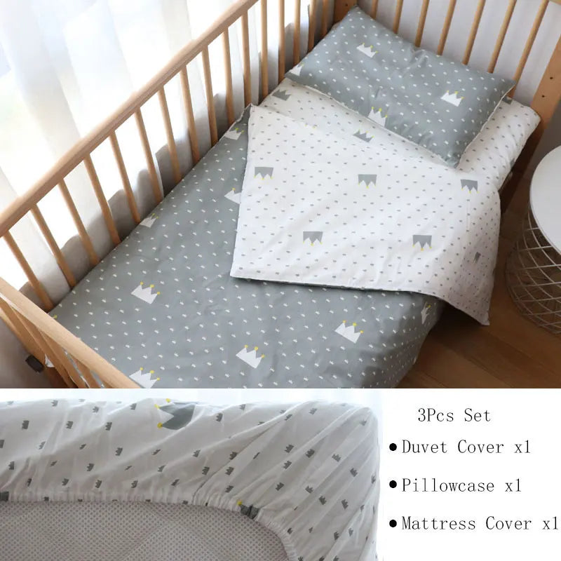 A crib features a grey and white bedding set with a crown pattern, including a duvet cover, pillowcase, and fitted mattress cover, styled in a cozy, sunlit nursery.