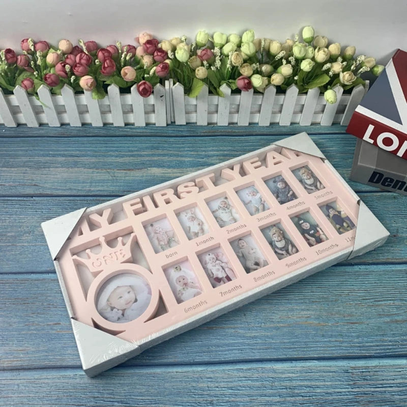 A pink picture frame titled "My First Year" holds twelve baby photos labeled by month, from birth to 12 months. It's set on a wooden surface near a picket fence with roses.