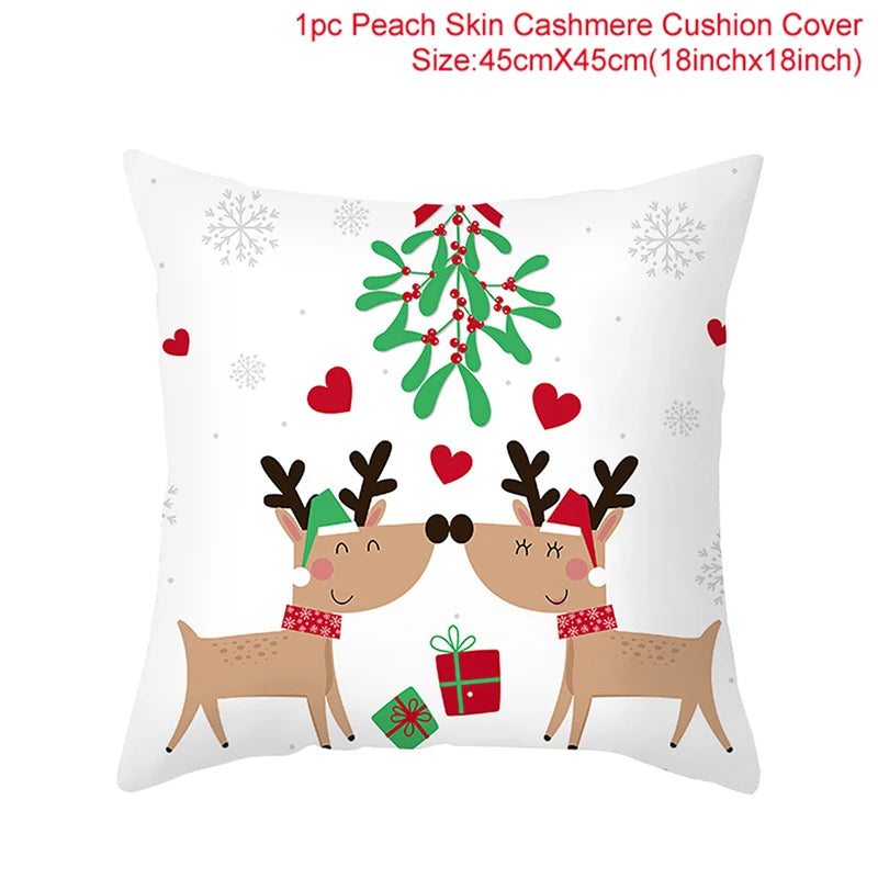 Cute reindeer wearing festive hats and scarves touch noses under mistletoe, surrounded by snowflakes and hearts on a white cushion cover. Gifts rest below them.