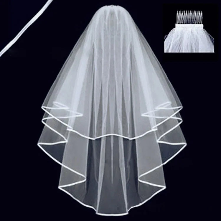 A two-tiered white bridal veil with ribbon edging is displayed on a dark background. An inset shows a close-up of the comb used for securing the veil.