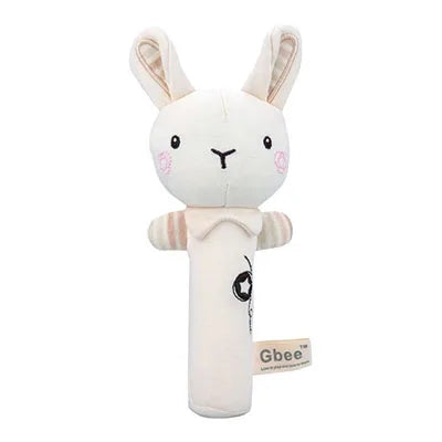 A soft, plush baby rattle shaped like a bunny with white fabric, embroidered face, and light pink cheeks. It has floppy ears, small striped arms, and a Gbee label on the side.