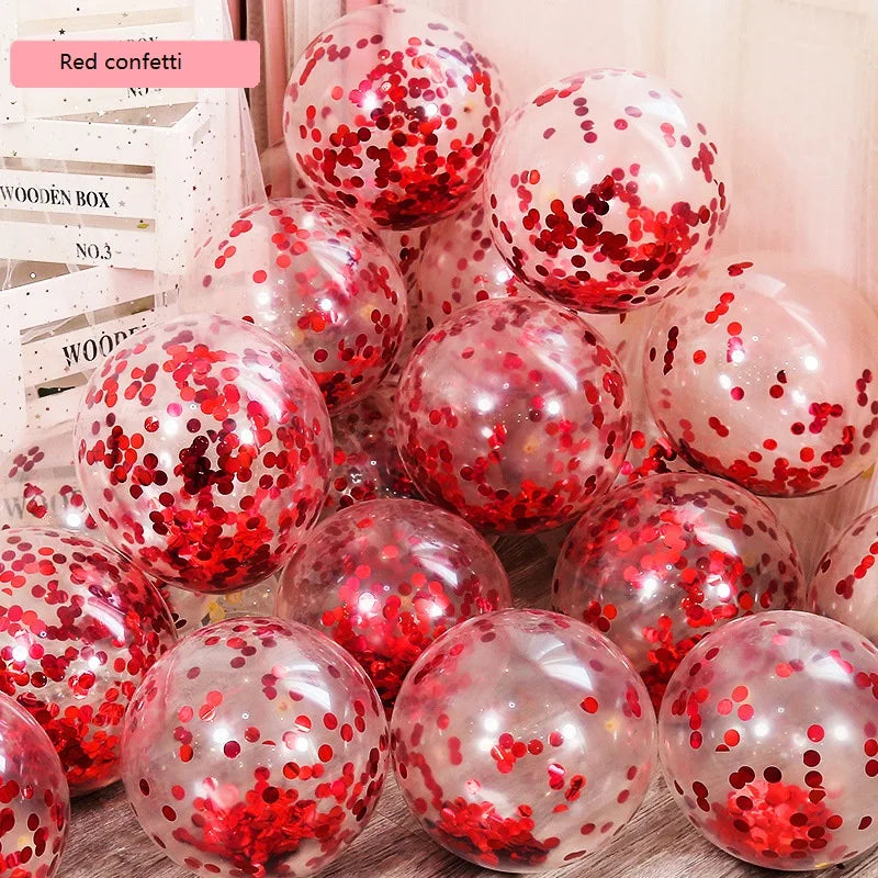 Clear balloons filled with red confetti are clustered together beside white wooden boxes. The balloons' surfaces reflect light, creating a festive atmosphere.