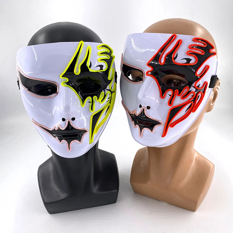 Two mannequin heads wearing masks with neon accents. The left mask features yellow and black designs; the right mask has red and black patterns. Both are on plain stands.