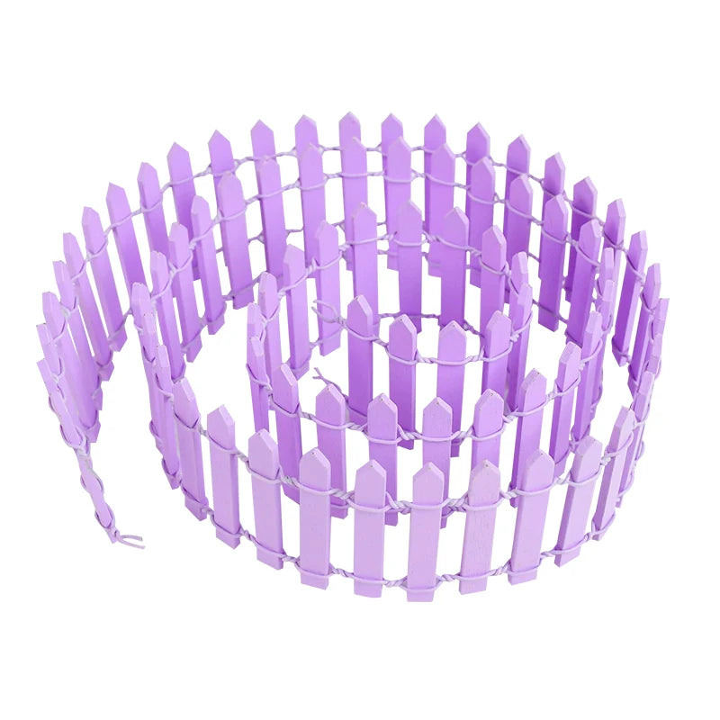 Coiled roll of purple wooden picket fence arranged neatly, ready for use. The fence features pointed tops and is secured with wire, designed for decorative or garden use.