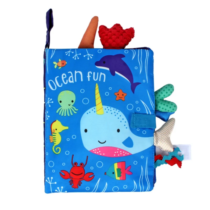Bright children's fabric book titled "Ocean Fun" featuring a narwhal, dolphin, octopus, seahorse, crab, and fish on a blue ocean-themed cover with textured tabs.