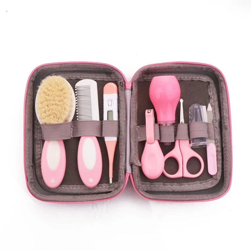 Pink baby grooming kit with a brush, comb, thermometer, nasal aspirator, nail clippers, scissors, and a nail file, neatly organized in a soft gray-lined case.