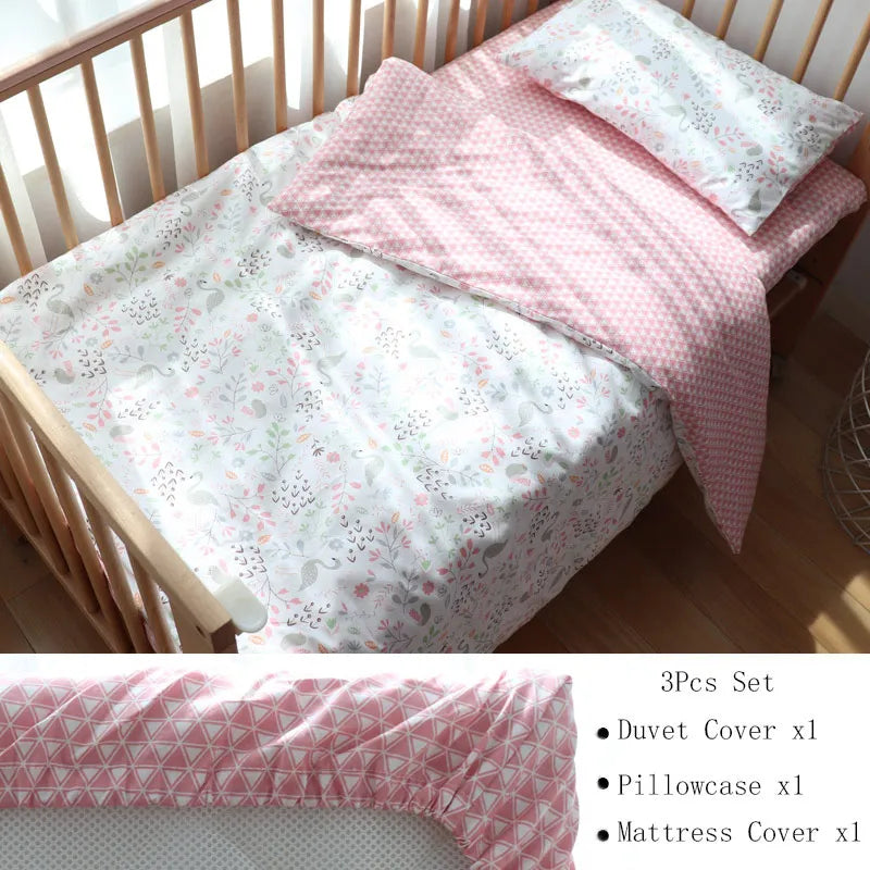 A baby crib with a floral-patterned sheet, pink checkered duvet cover, and matching pillowcase. Set includes a duvet cover, pillowcase, and mattress cover. 3-piece set description shown.