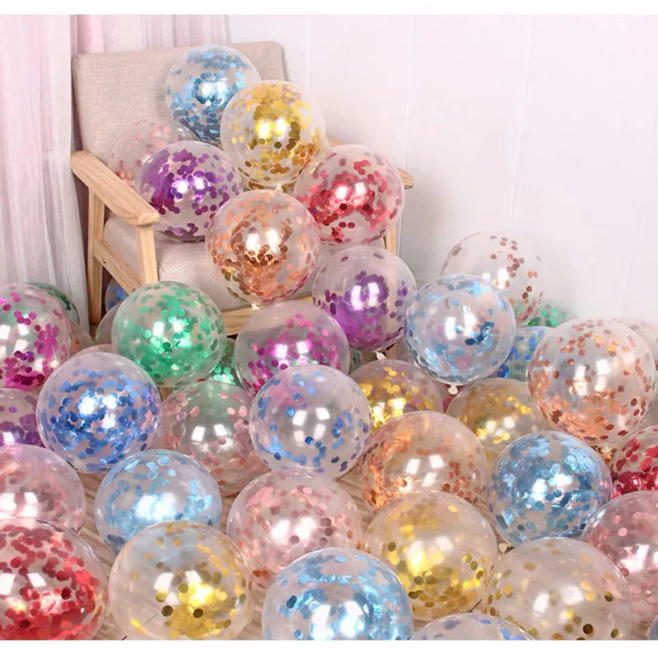 Transparent balloons filled with colorful confetti are scattered around and on a beige armchair. The balloons feature hues of blue, gold, red, green, and more, creating a festive atmosphere.