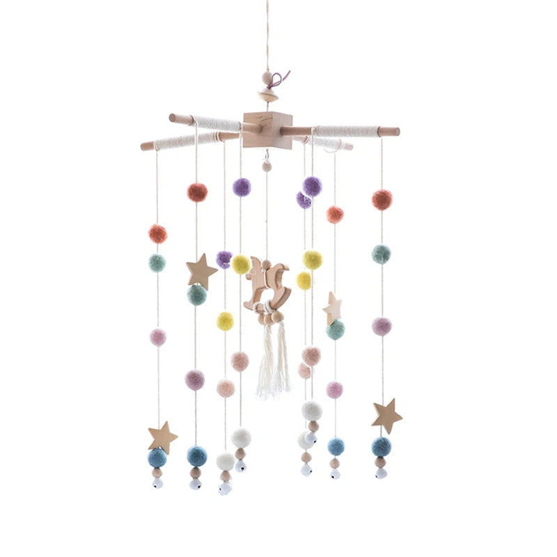 Wooden baby mobile with colorful pom-poms, stars, and animal shapes hanging from strings. Features vibrant hues of purple, orange, blue, yellow, and pink.