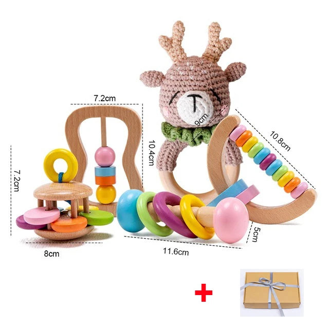 Set of colorful wooden baby toys, including a rattle with a crocheted deer, ring stacker, and bead roller with attached dimensions. A gift box is also shown below.
