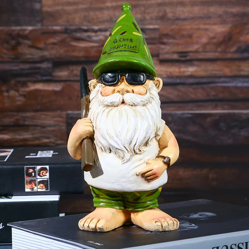 A garden gnome with a white beard, wearing sunglasses and a green hat that reads "Gone Huntin'," holds a rifle. It stands on books against a wooden backdrop.