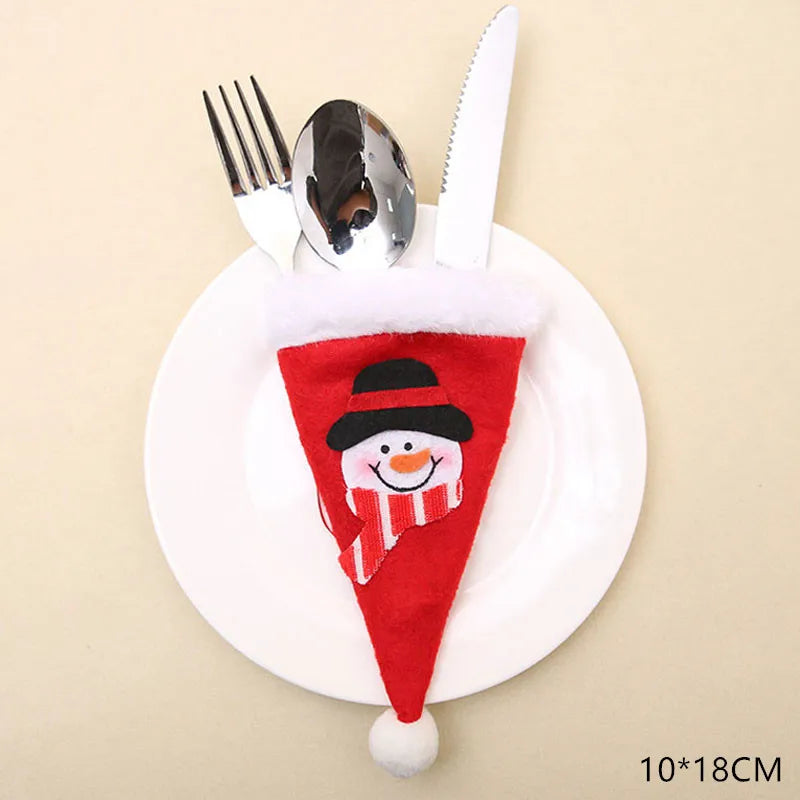 A plate holds a red felt cutlery holder shaped like a Santa hat, featuring a smiling snowman design. It contains a fork, spoon, and knife. Dimensions: 10x18 cm.