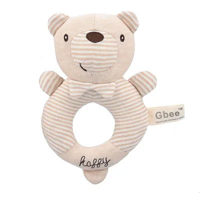A soft, beige teddy bear-shaped baby rattle with striped arms and a circular cut-out body. Embroidered with "happy" and labeled "Gbee."