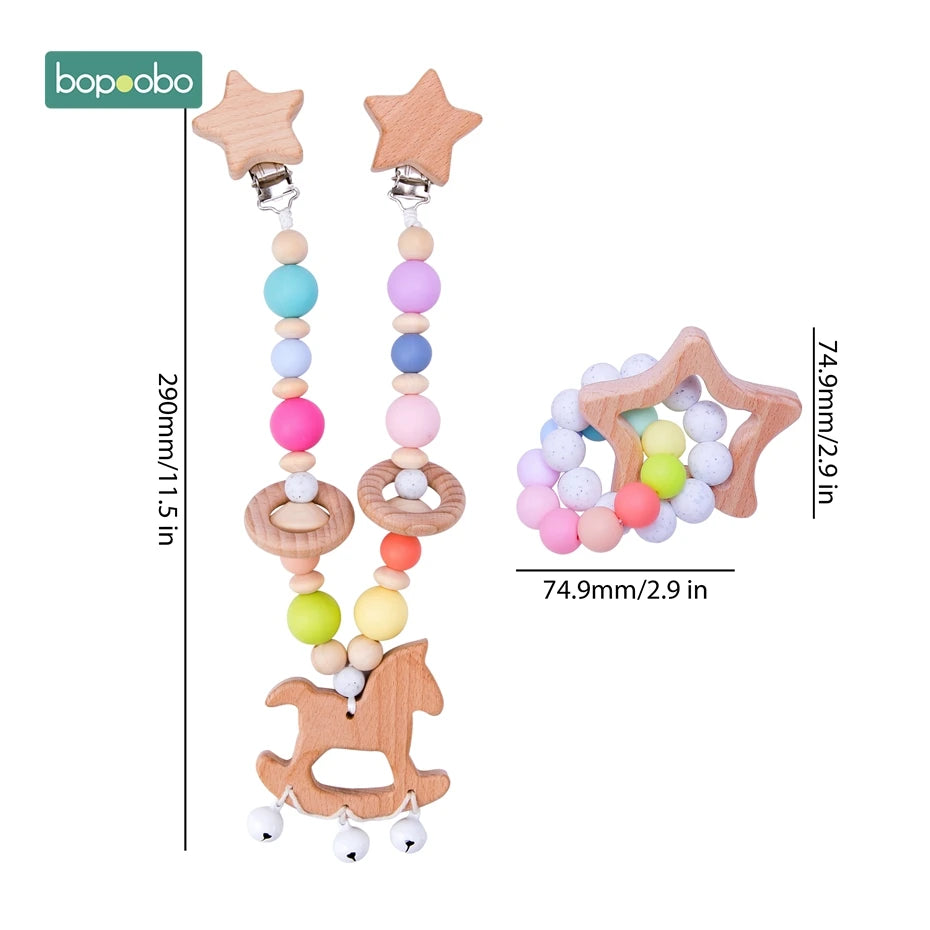 Wooden baby pacifier clip and teether set. The pacifier clip features colorful beads and a rocking horse design, 290mm long. The teether is star-shaped, 74.9mm in diameter.