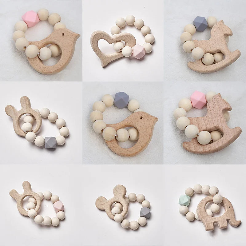 Wooden baby teethers shaped like animals and hearts, made with natural beads and hexagonal accents in soft pastel colors, arranged on a plain background.