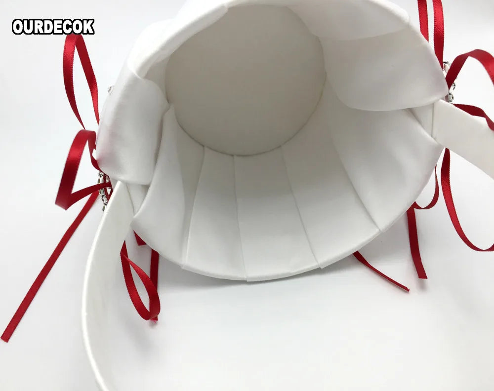 White fabric handbag with pleated design, viewed from the top. Red ribbons accent the sides, adding a touch of color and elegance to the simple design.