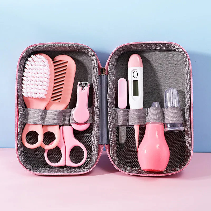 Pink baby care kit with a brush, comb, nail clippers, scissors, thermometer, nasal aspirator, and finger toothbrush arranged neatly in a soft pink zippered case.