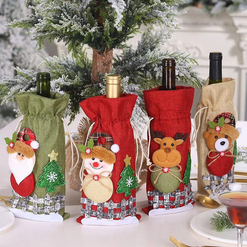 Four wine bottles are dressed in festive holiday bags featuring decorations of Santa, a snowman, reindeer, and a bear. They are set on a table with a snowy tree backdrop.