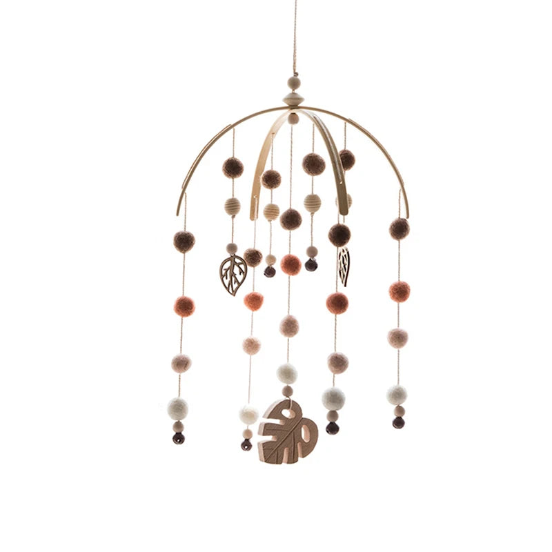 Hanging mobile with wooden hoops, felt balls in warm tones, and leaf-shaped ornaments on strings.