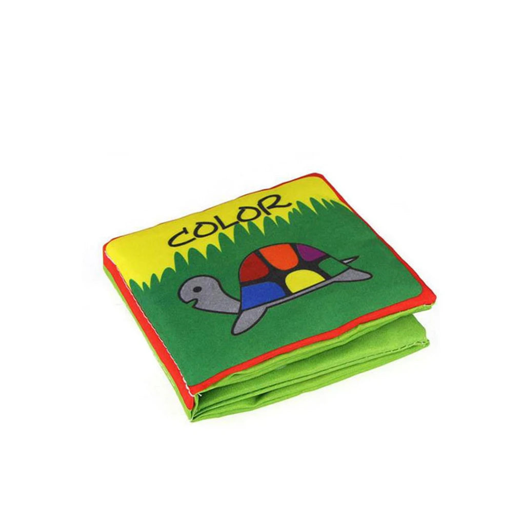 Children's soft fabric book with a colorful turtle illustration on the cover. The word "COLOR" is printed above, surrounded by grass, with red and yellow borders.