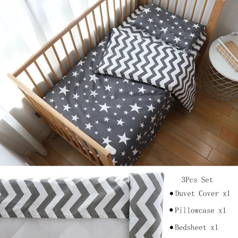 A wooden crib with a set of bedding featuring dark gray fabric with white stars and a chevron-patterned blanket. Includes duvet cover, pillowcase, and bedsheet.